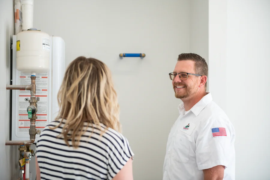 Thompson Plumbing tech explaining a water heater system to a homeowner during a service call in the St. George Utah area