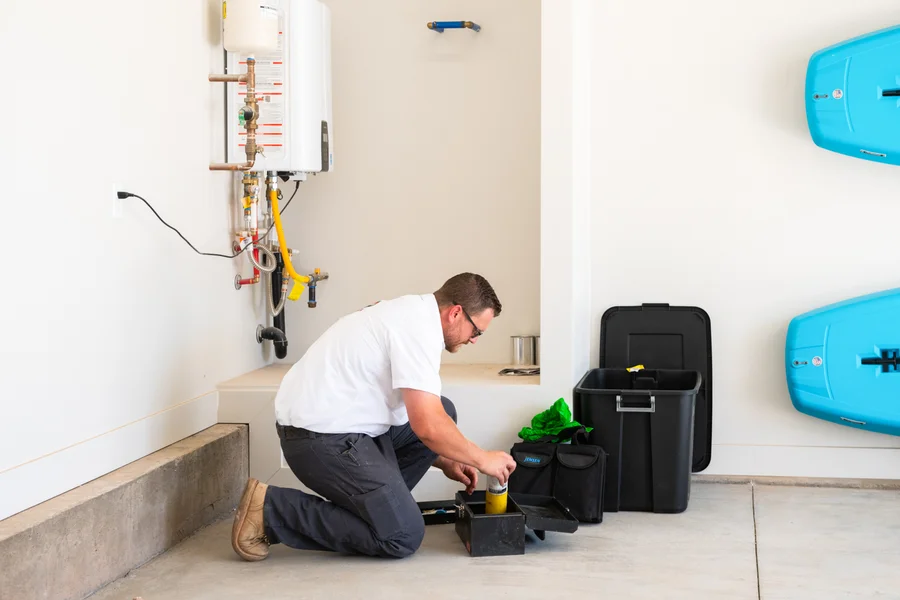 Thompson Plumbing technician Carlin inspecting water heater connections and valves with a St. George Utah homeowner on-site