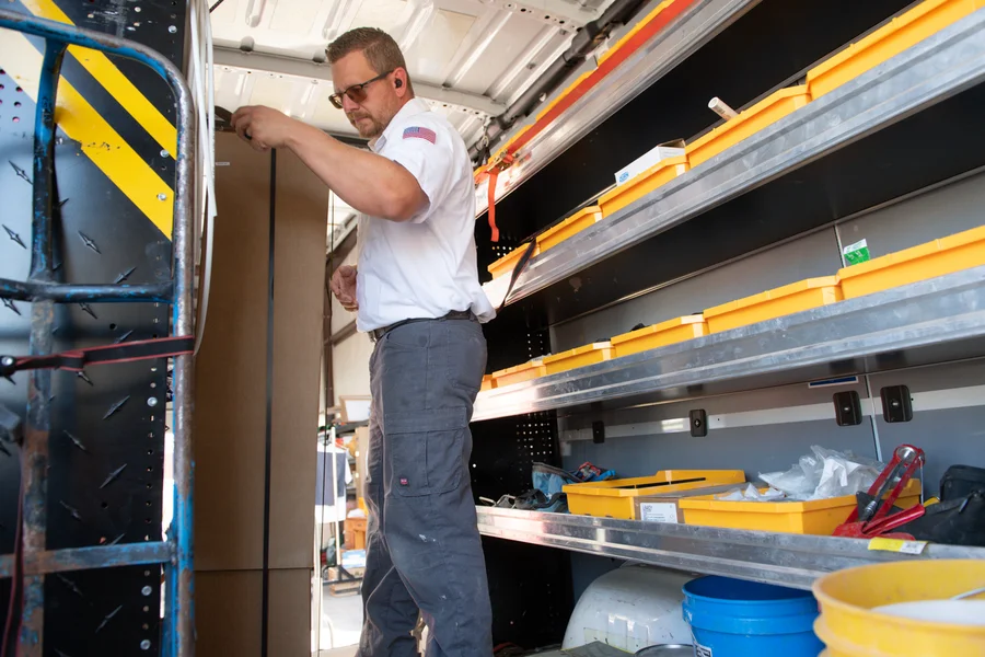Thompson Plumbing technician organizing a fully stocked service van with shelved parts and supplies ready for St. George Utah calls