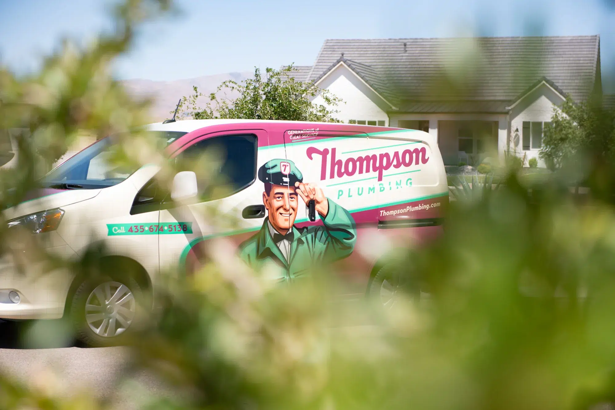 Thompson Plumbing service van seen through landscaping outside a Washington County Utah home