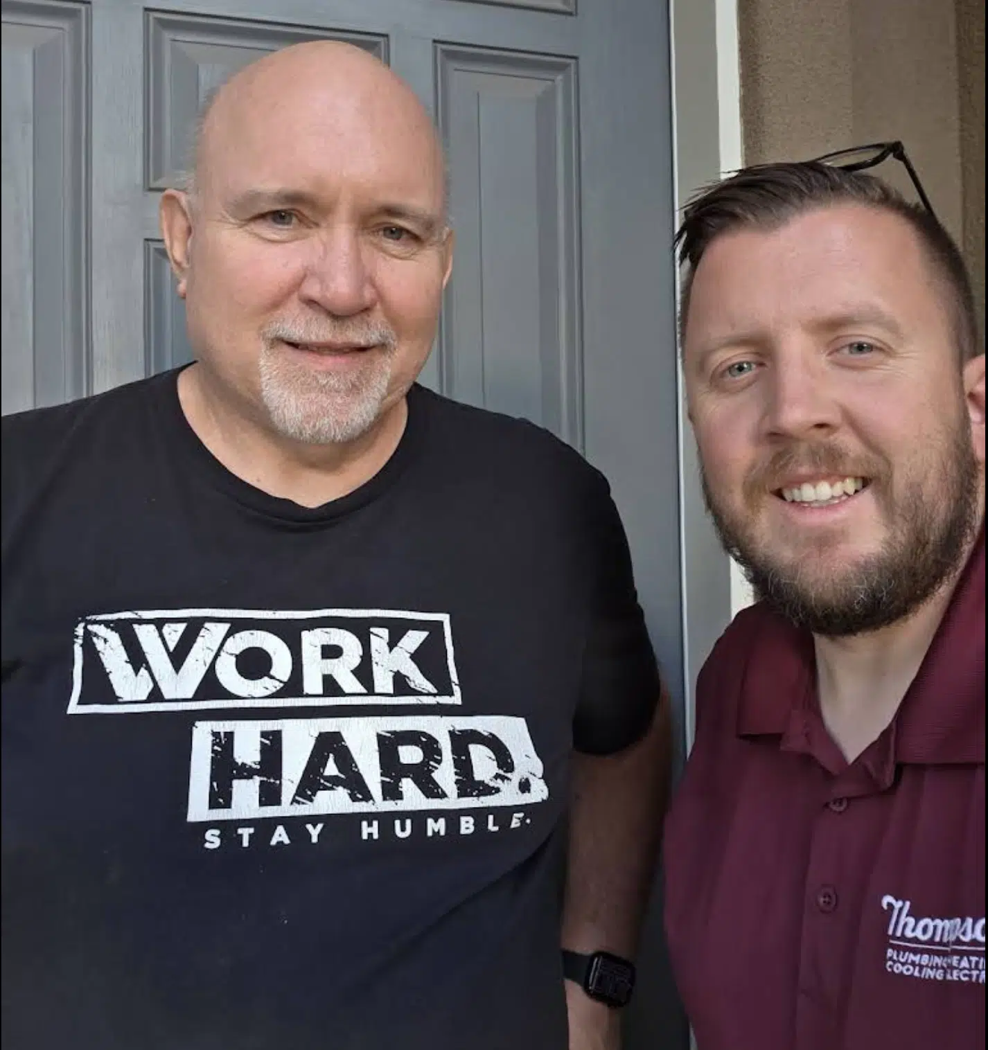 Satisfied homeowner posing with a Thompson Plumbing, Heating, Cooling & Electrical technician after a completed service call