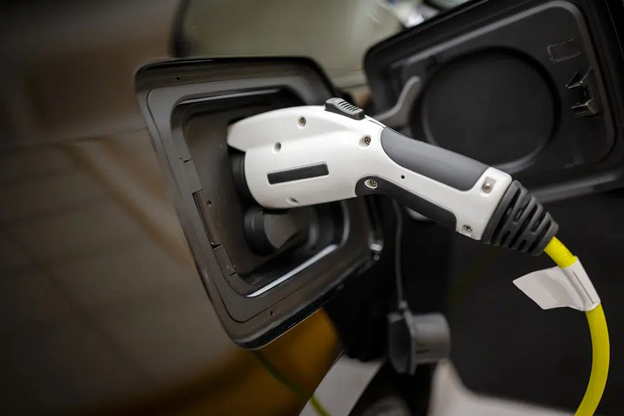 A close-up of a electric vehicle charging connector plugged into the charging port of a car