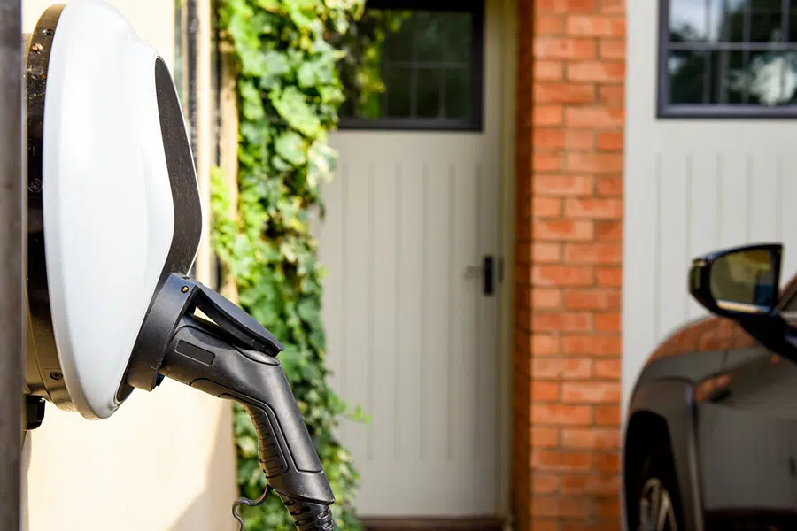 A St George home EV charging unit mounted on an exterior wall with electric vehicle nearby