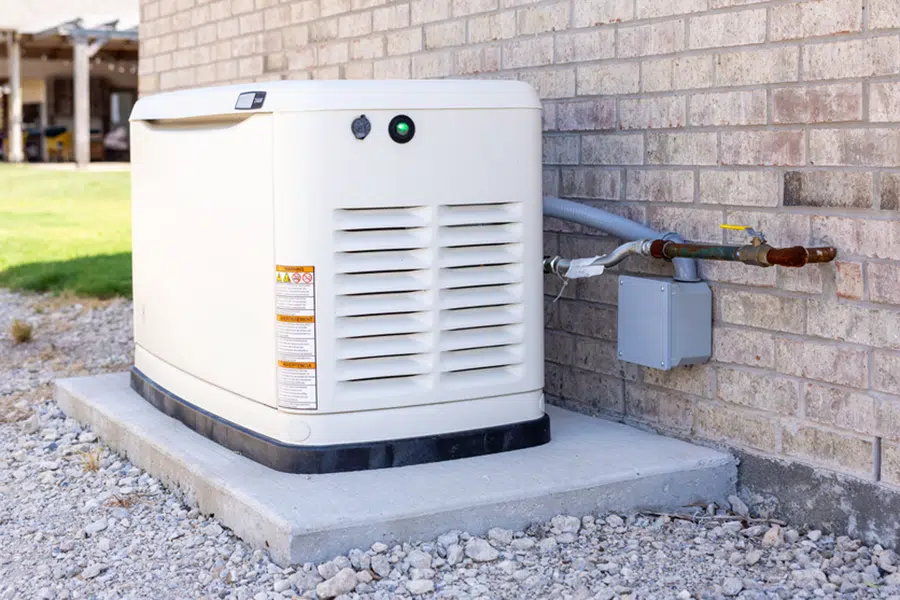 White standby home generator installed on a paver pad beside a stone home in St. George, Utah.