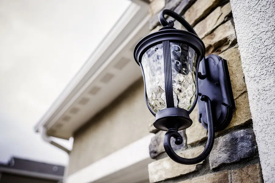Black iron outdoor wall sconce on a stone home — expert exterior lighting installation in St. George, Utah.