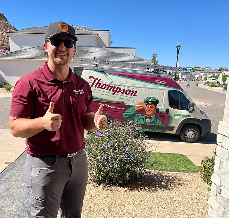 Smiling Thompson Plumbing, Heating, Cooling, and Electric technician giving thumbs up outside a St. George Utah home